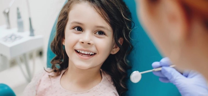 Bambina sorridente sulla poltrona durante una visita nello studio dentistico a Pomezia